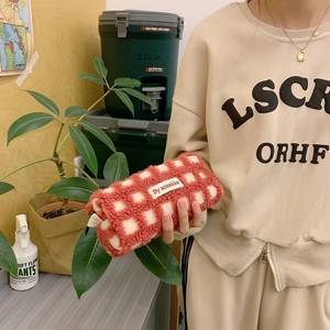 Close-up of a plush red and white checkered waffle pattern pencil case with brand label