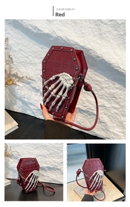 Detail of red coffin-shaped handbag with embossed skulls and 3D skeleton hand charm