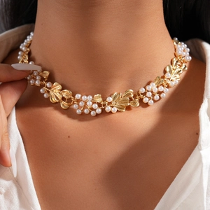 Detailed view of vintage gold leaf necklace with elegant white pearls on a model neck