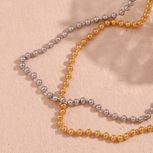 Detail of 4mm bead chain necklaces in 18K gold and silver finishes on a soft background