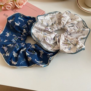 Close-up of floral fabric scrunchies in navy and cream with elegant satin sheen finish
