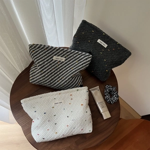Close-up of woven fabric makeup bags with polka dots and stripes on a wood table