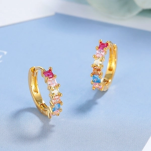 Golden geometric hoop earrings with vibrant colorful cubic zirconia stones in macro view
