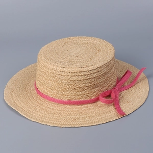 Macro detail of the woven raffia texture and fuchsia ribbon on this flat sun hat