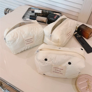 Gros plan détaillé de trousses de maquillage matelassées crème avec dentelle et pois