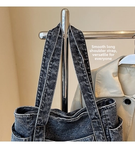 Detail of grey washed denim tote bag featuring wide shoulder straps and contrast stitching