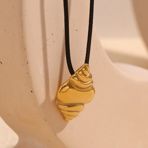 Macro shot of 18K gold plated conch shell pendant on a minimalist black wax cord necklace