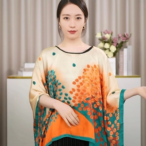 Detail eines Seidensatin-Ponchos mit lebendigem orangefarbenem und grünem Blattmuster