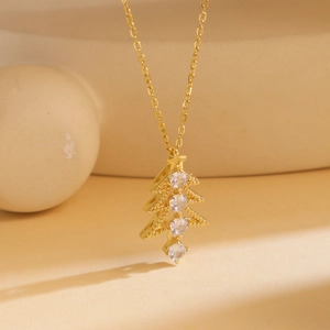 Macro detail of a golden Christmas tree pendant necklace with clear zircon stones