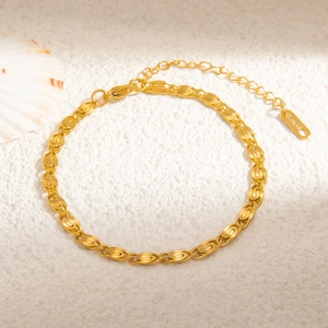 Detail view of gold stainless steel link bracelet with S.steel tag on white sand