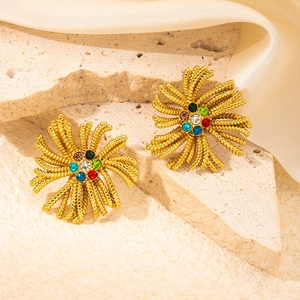 Detailed shot of gold flower earrings with colorful zircons on a textured stone background