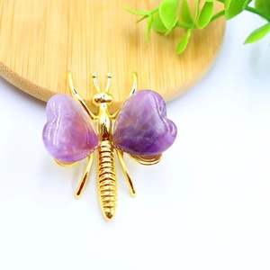 Detail of a gold butterfly brooch with purple heart-shaped amethyst crystal wings