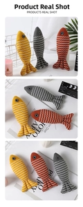 Close-up of three linen fish-shaped catnip toys in yellow, grey, and orange colors