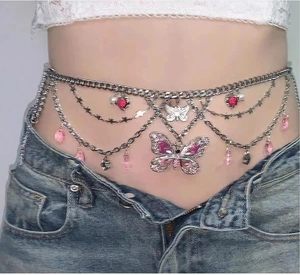 Detail of Y2K silver layered waist chain with pink butterfly and star charms on denim