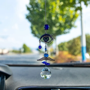 Blue Evil Eye suncatcher with crystal prism ball and metal wings hanging in a car