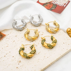 Detailed shot of three pairs of twisted U-shaped earrings with rhinestones on silk