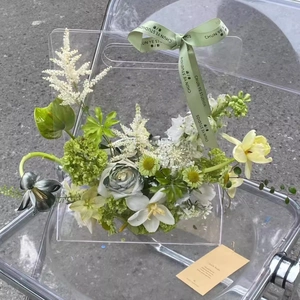 Détail d'une boîte à fleurs en acrylique triangulaire avec des lys blancs et ruban vert