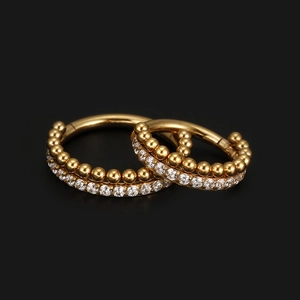 Goldene Edelstahl-Ohrringe mit Zirkon-Steinen und Goldperlen auf schwarzem Hintergrund