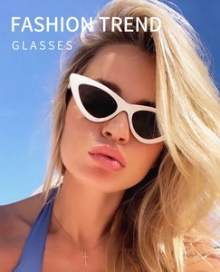 Close-up of woman wearing cat eye sunglasses with white frame and black lenses outdoors
