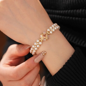 Détail d'un bracelet en perles double rang avec pendentif en pierre orange et or sur le poignet