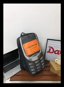 Detailed retro mobile phone shaped backpack on wooden bench with creative orange screen art