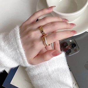 Close-up of gold layered rings and wavy band on a hand with minimalist luxury aesthetic
