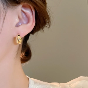 Close-up of a high-polished 18K gold plated teardrop earring worn by a model