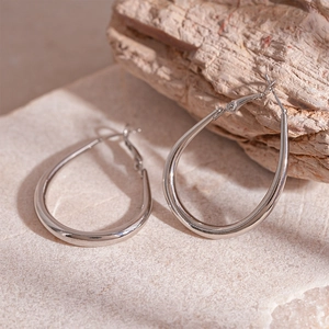 Close-up of polished silver teardrop earrings on natural stone surface with macro detail