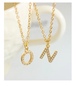 Close-up of titanium steel necklaces with gold letter pendants O and N set with cubic zirconia