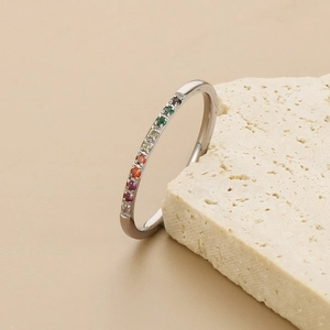 Rainbow gemstone band ring in silver finish on a minimalist cream stone background