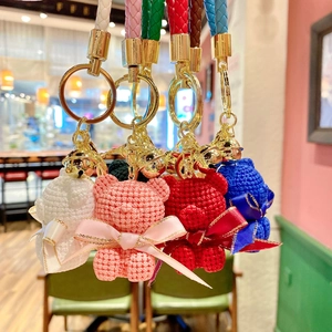 Detailed view of colorful knit resin bears with golden bells and braided leather straps