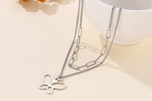 Close-up of double-layered silver necklace with hollow butterfly pendant and paperclip chain