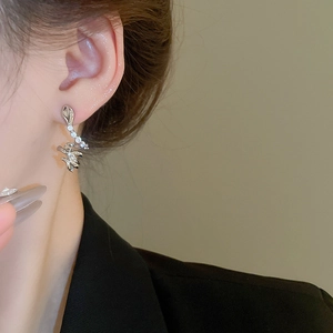 Close-up of curved snake stud earrings with zircon stones on female ear