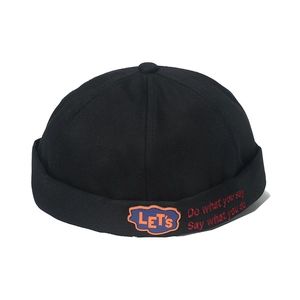 Streetwear black canvas docker hat with orange lettering and red embroidery on white background