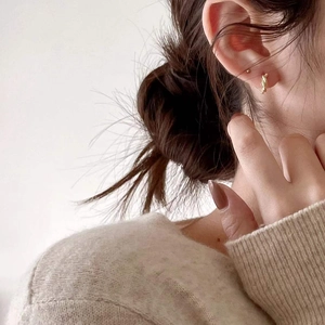 Close-up of minimalist gold twisted knot earrings worn by a model for a modern look