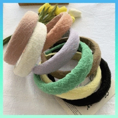 Assorted soft coral fleece bow headbands in multiple pastel colors on a textured surface