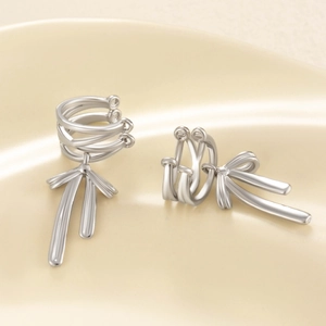 Elegant silver multi-loop bow pendant clip-on earrings for women on beige background