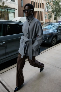Detail of grey wool-like short coat featuring a stand collar and adjustable waist belt