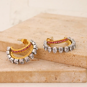 Detail of gold double-layer C-shaped earrings with pink crystals and clear zircon