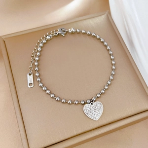 Detailed macro shot of a full diamond heart pendant on a silver beaded chain bracelet
