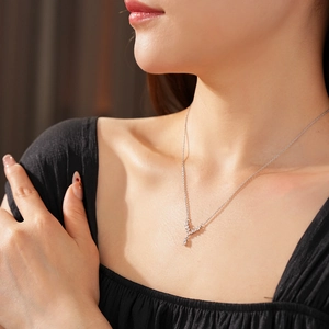 Close-up of a silver V-shaped necklace with zircon drop pendant on model neck