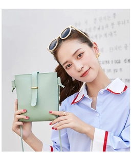 Detail of mint green cross-body phone bag with lychee texture and gold clasp detail