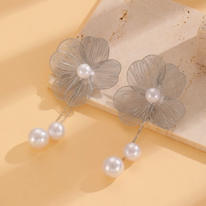 Detail of silver hollow flower earrings featuring elegant cascading white pearls on stone