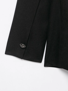 Detail of wool blend coat showing black twill fabric and embossed metallic buttons