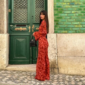 Detail of red floral print maxi dress with flared sleeves against a vintage door