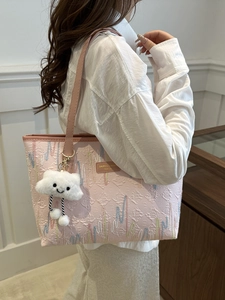 Pink jacquard tote bag with white cloud plush charm shown on model in a soft indoor setting