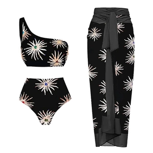 Detailed flat lay of three-piece black swimwear with sunburst pattern and sarong