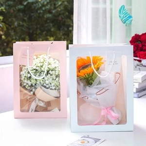 Close-up of rectangular pink gift bag with transparent PVC window and floral arrangement