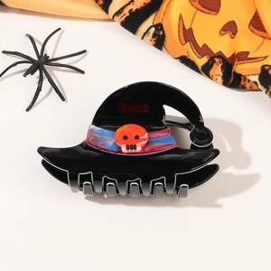 Close-up of Halloween witch hat claw clip with orange skull on festive background