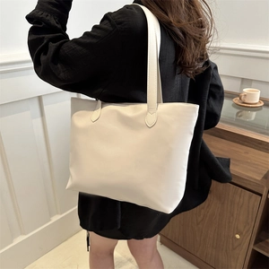 Minimalist white leather tote bag shown on shoulder of model in modern interior